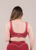 Person wearing a red sports bra and shorts set on a beige background