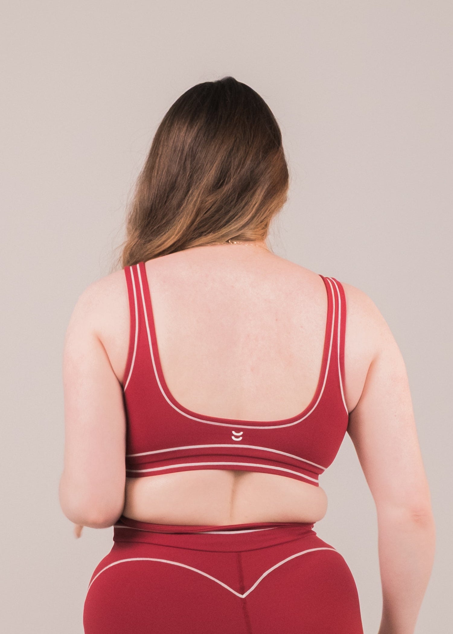 Person wearing a red sports bra and shorts set on a beige background