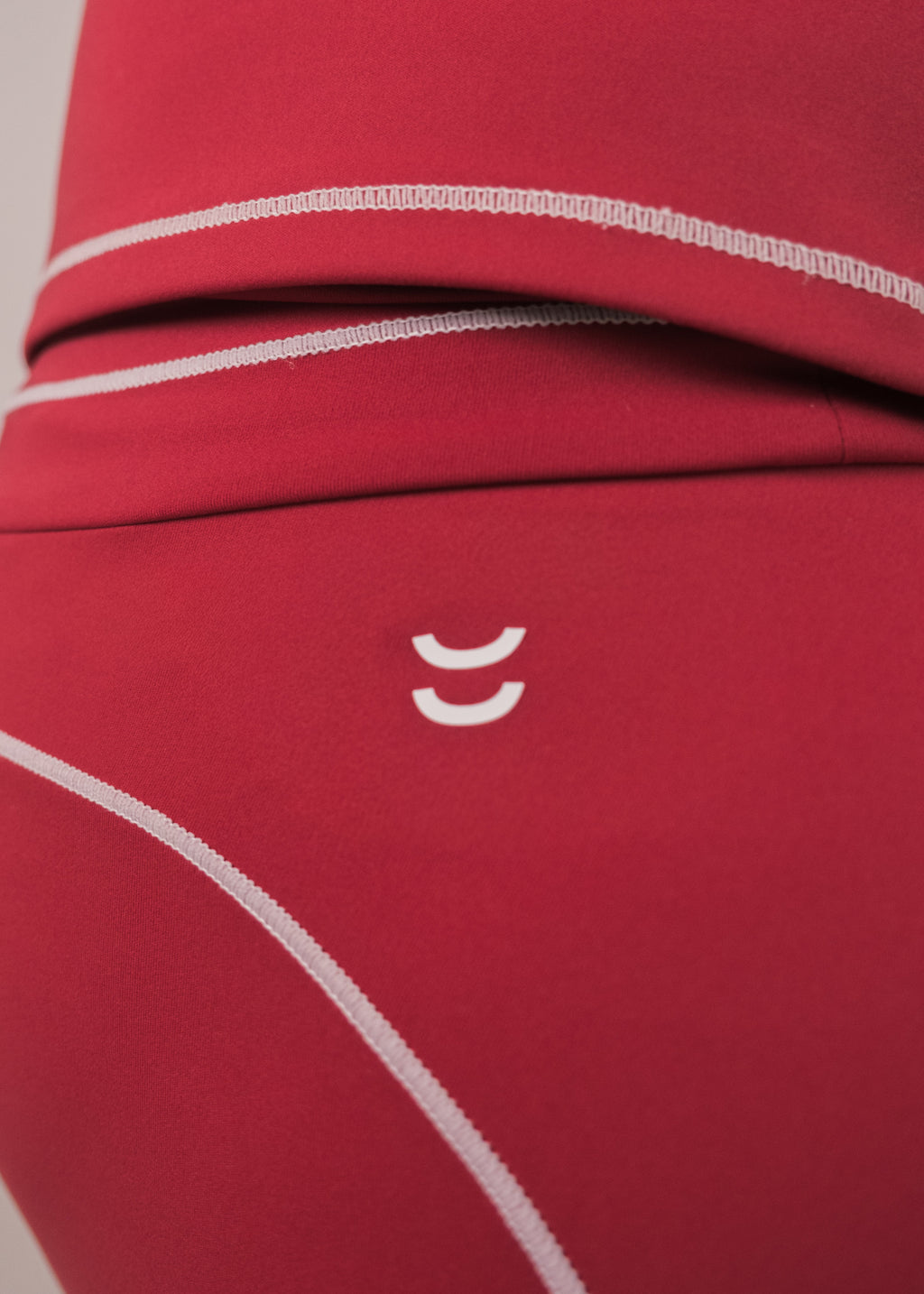 Close-up of red fabric with white stitching and a logo on a beige background