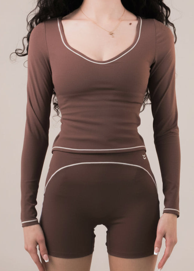 Woman wearing a brown athletic outfit on a beige background