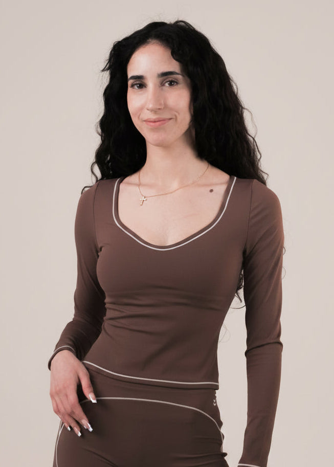 Woman wearing a brown long-sleeve top and pants on a beige background
