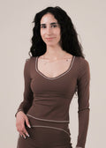 Woman wearing a brown long-sleeve top and pants on a beige background