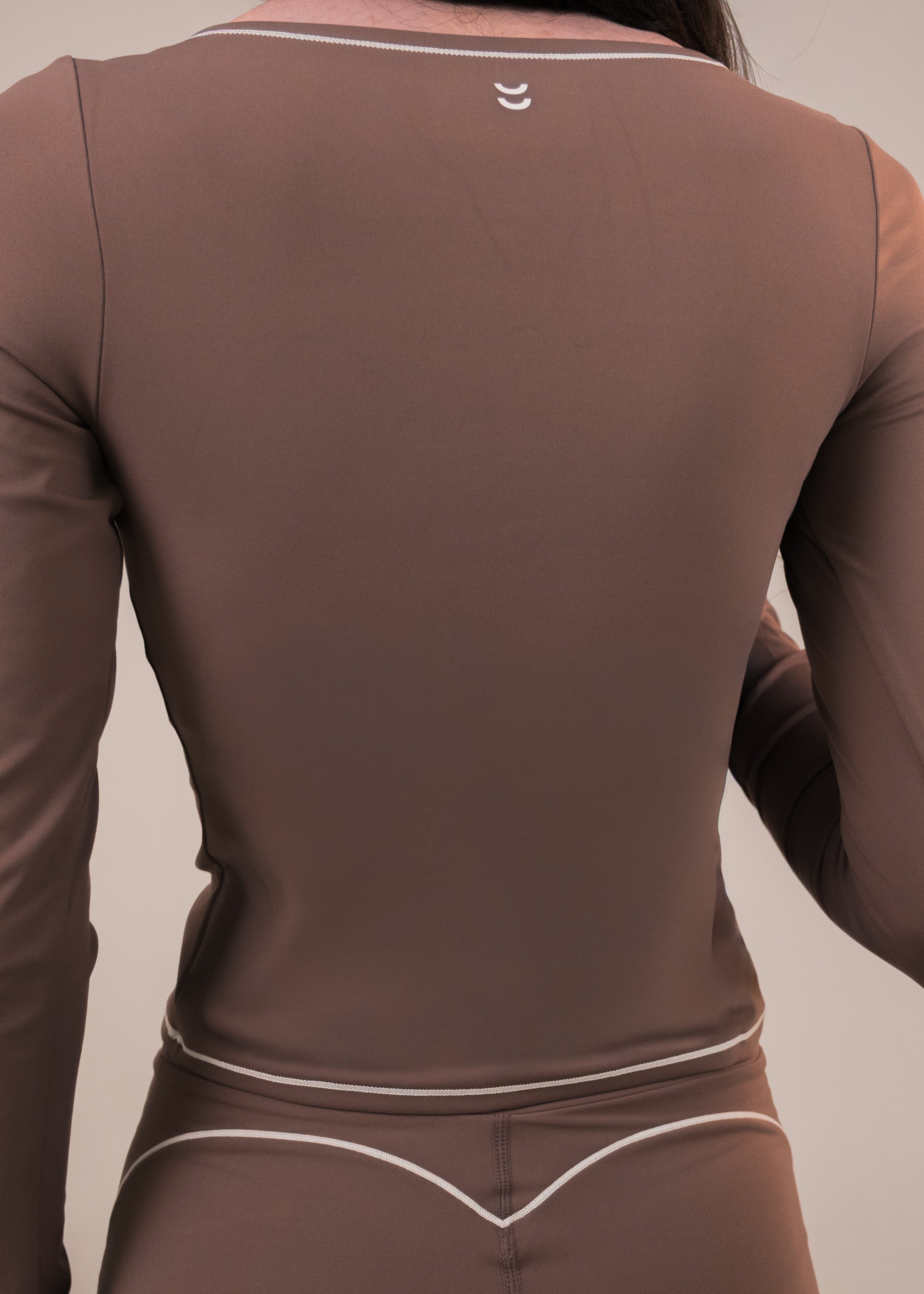 Brown long-sleeve athletic top with a logo on the back against a neutral background