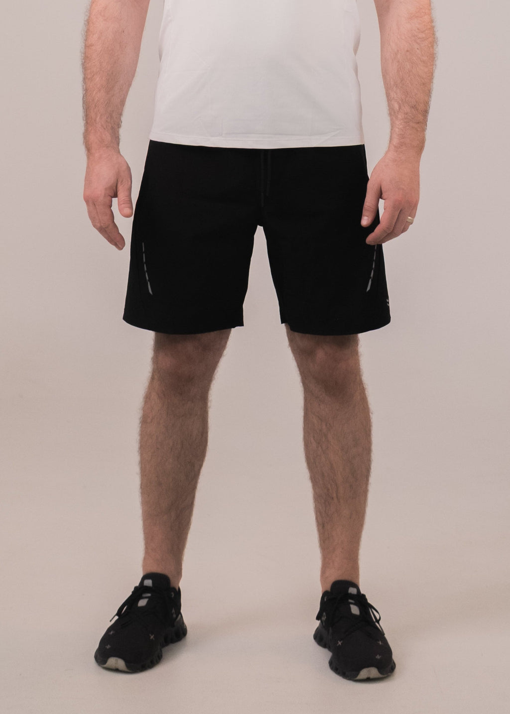 Man wearing a white t-shirt and black shorts on a plain background