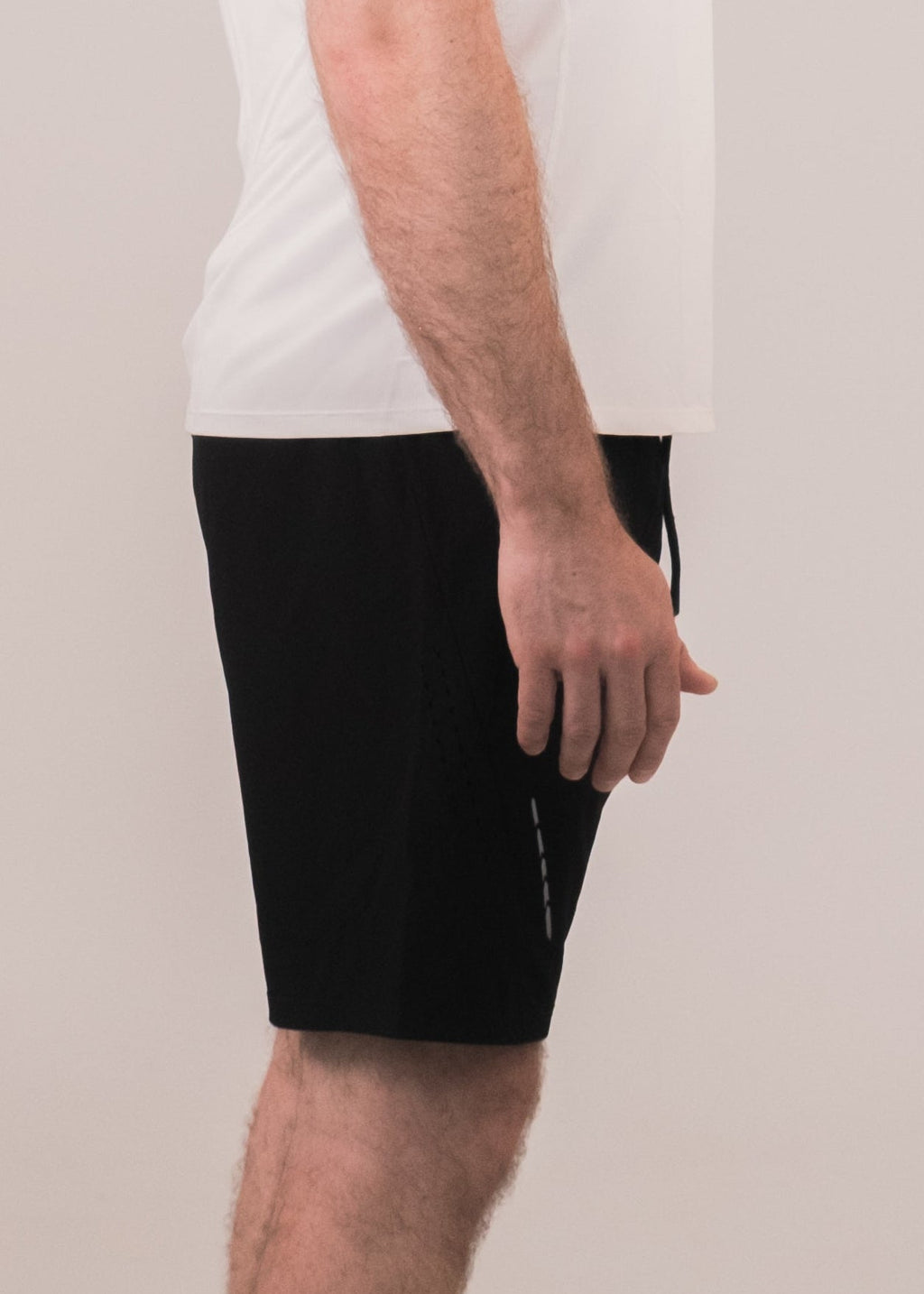 Man wearing a white t-shirt and black shorts standing against a plain background