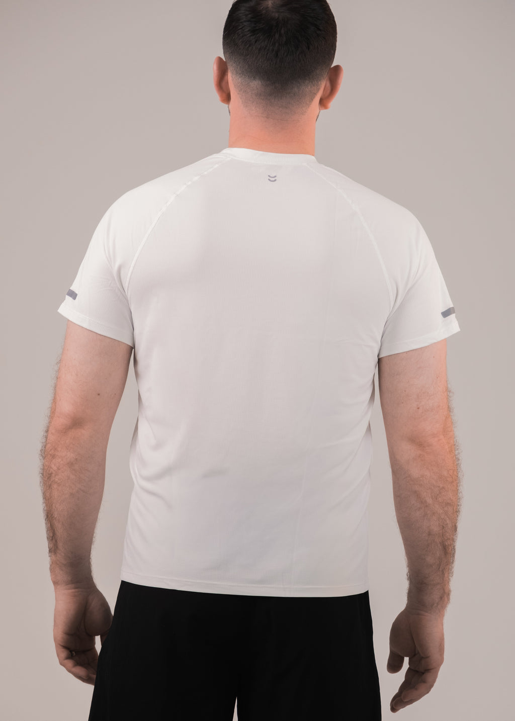 Man wearing a plain white t-shirt against a neutral background