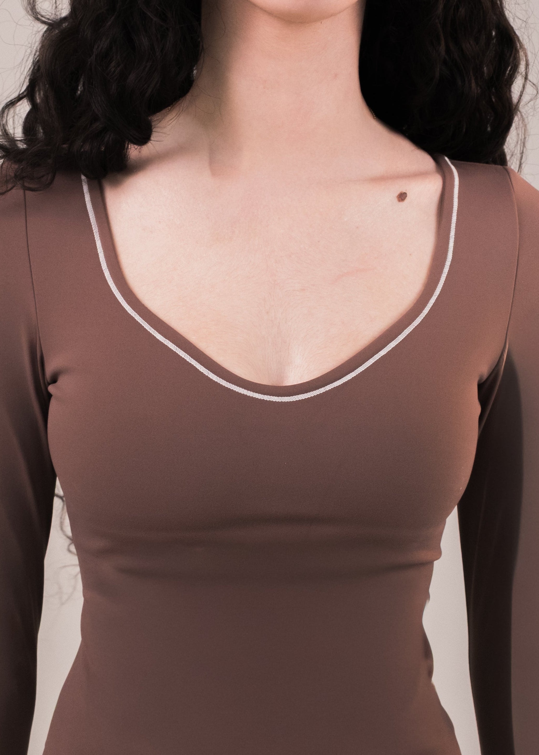 Brown long-sleeve top with white trim worn by a person on a neutral background