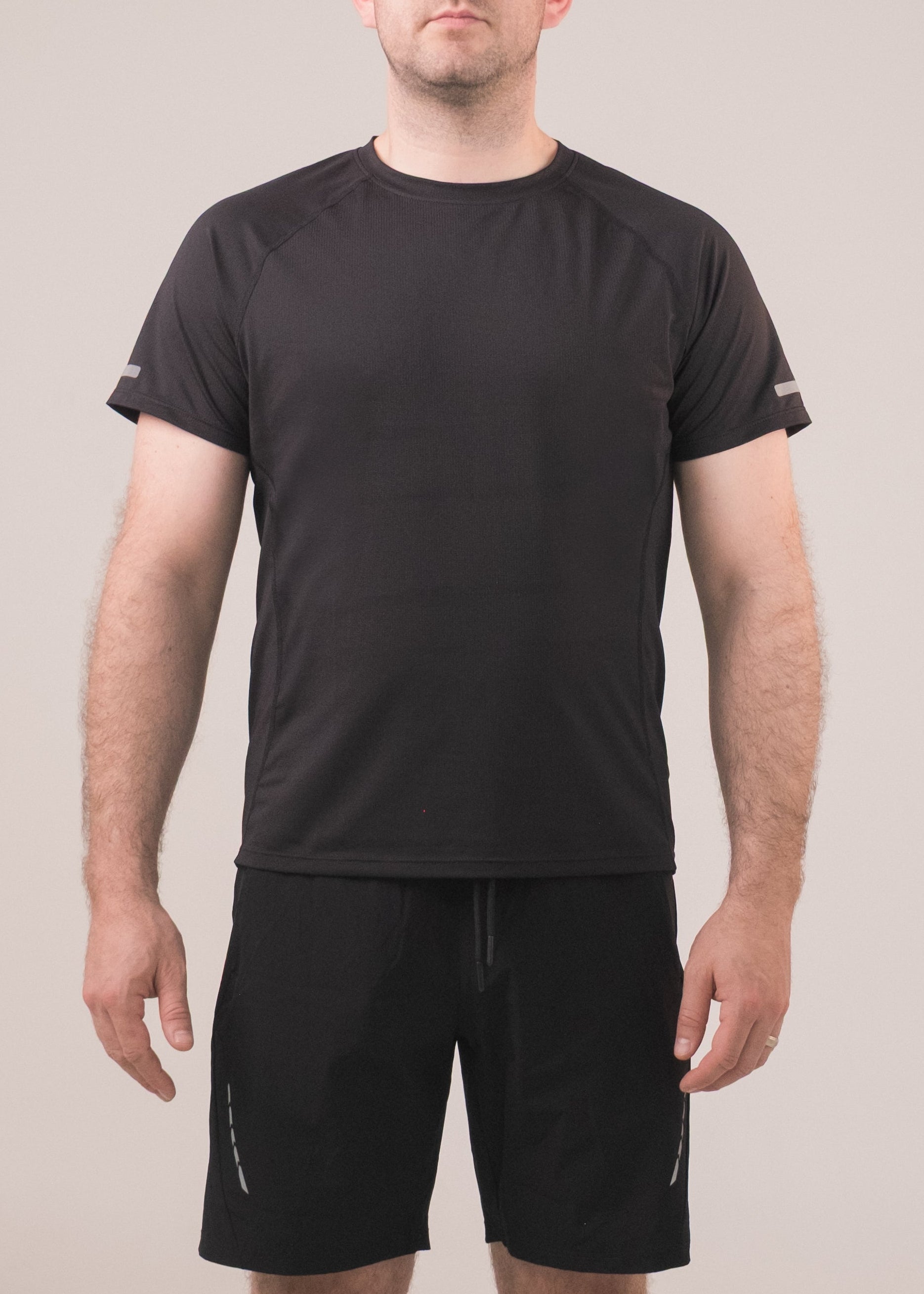 Person wearing a black t-shirt and shorts on a plain background