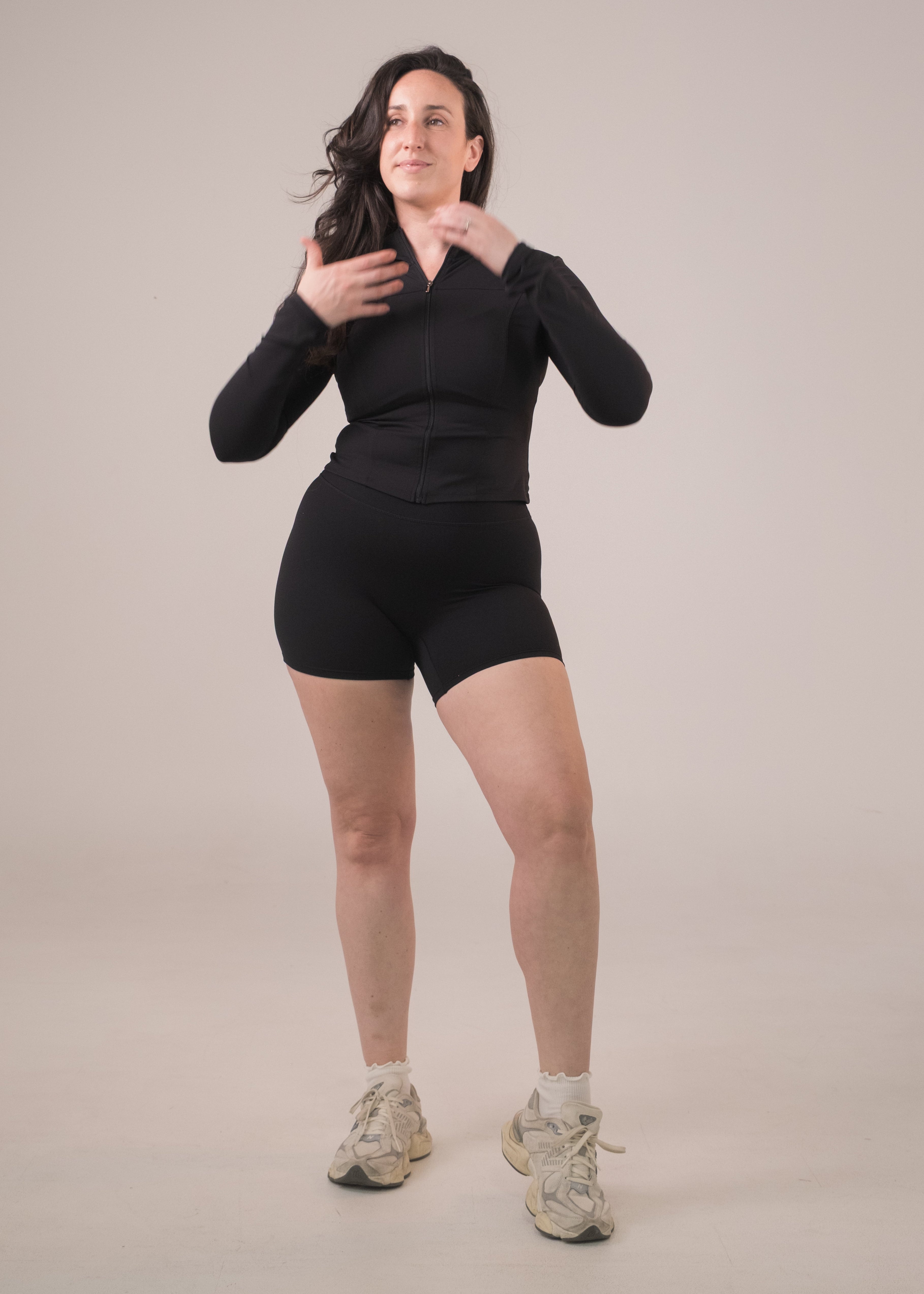 Woman wearing a black athletic outfit on a plain background