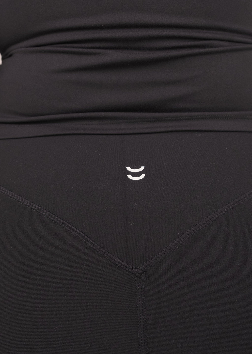 Black athletic outfit with a small logo on the waistband against a neutral background