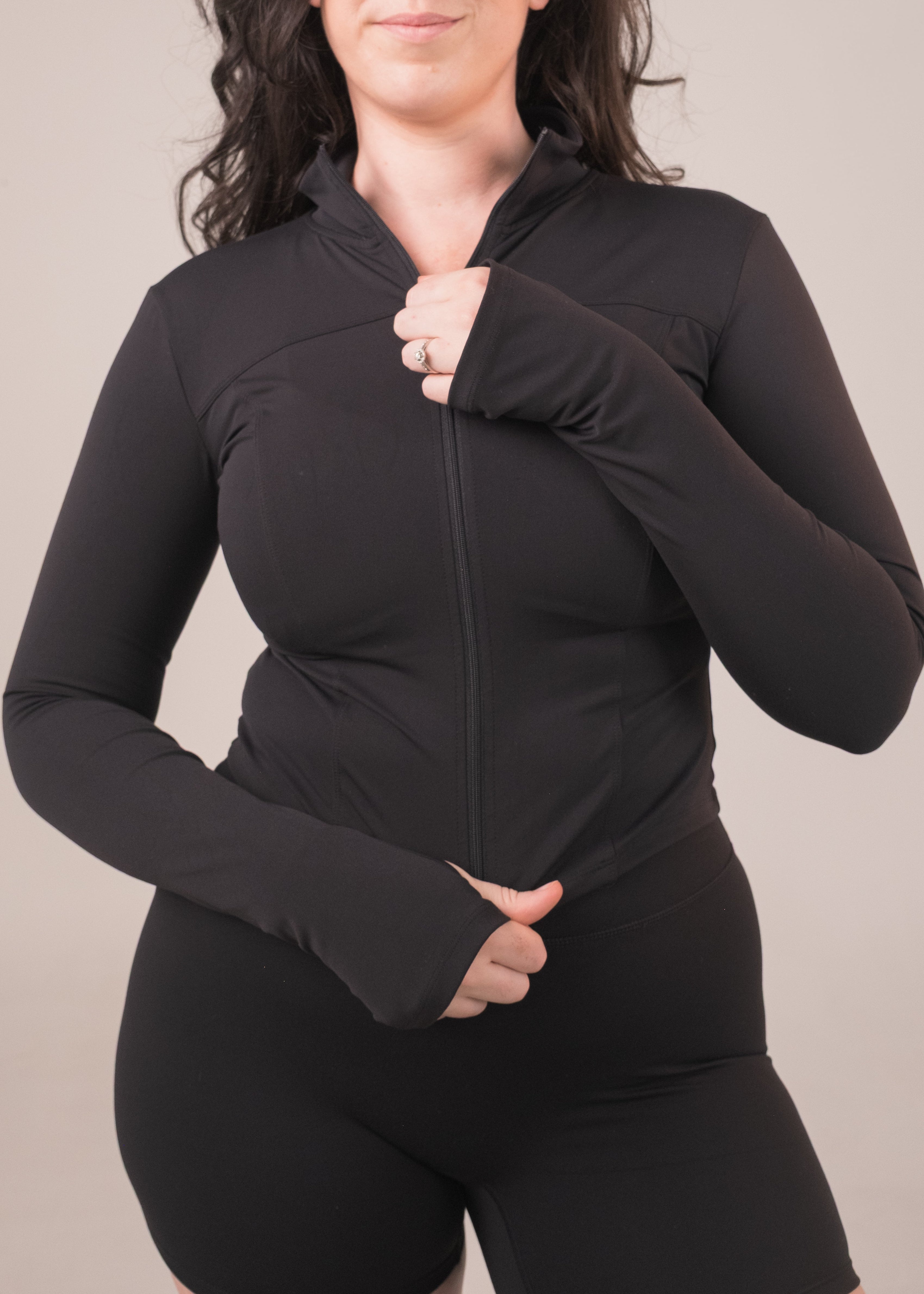 Woman wearing a black zip-up hoodie against a plain background