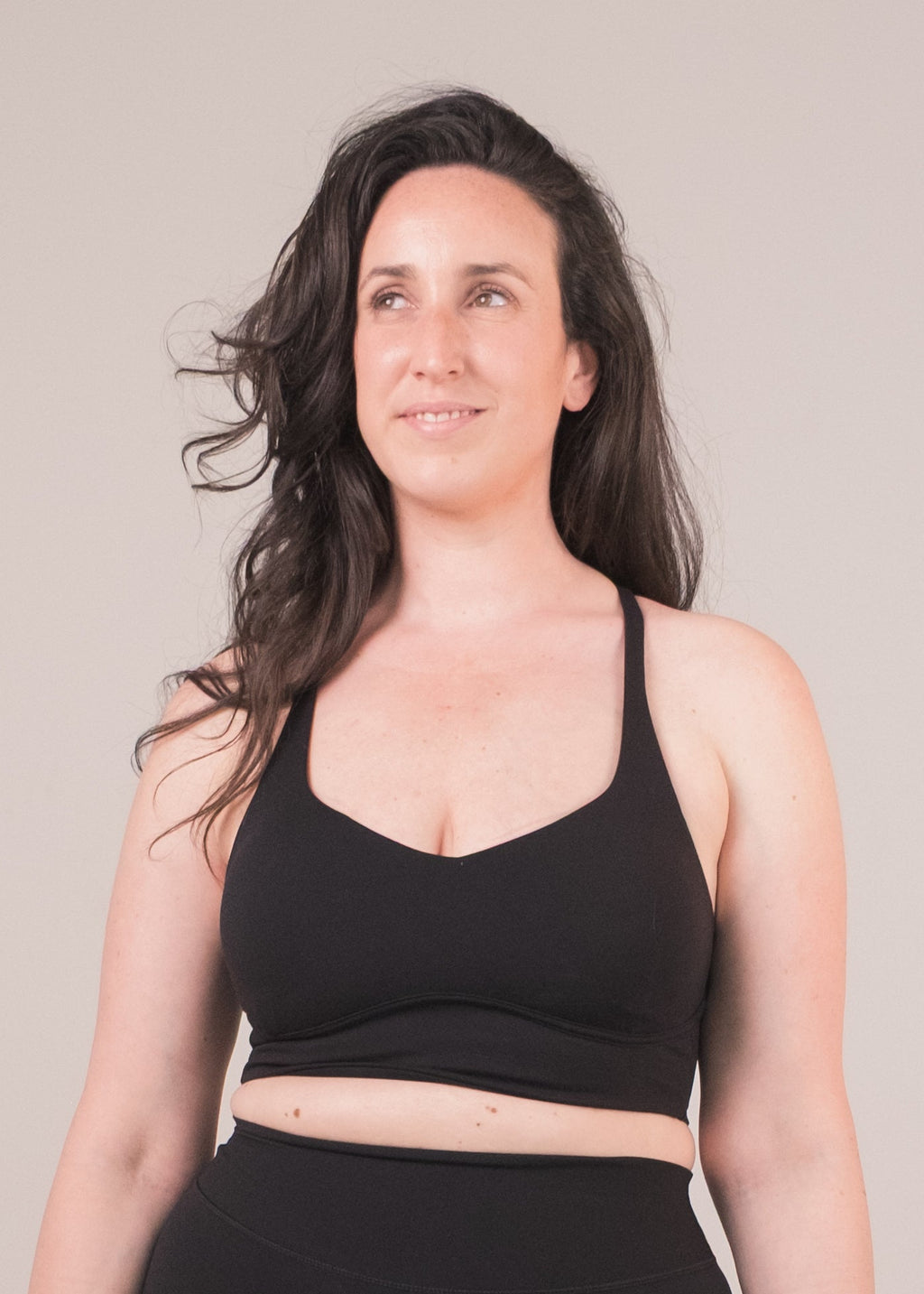 Woman wearing a black sports bra and shorts on a beige background