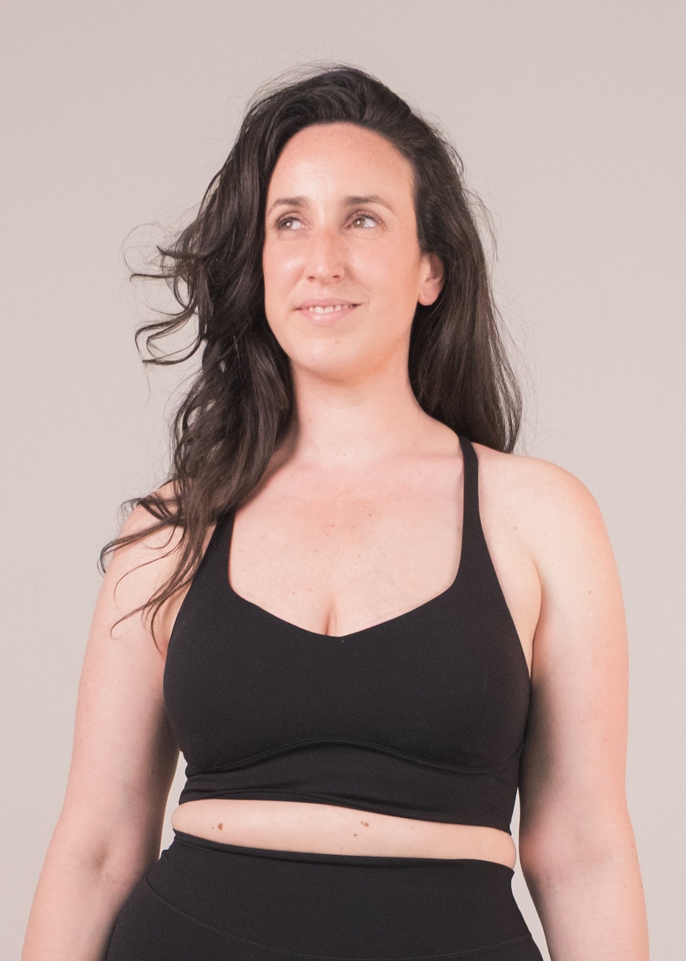 Woman wearing a black sports bra and shorts on a beige background