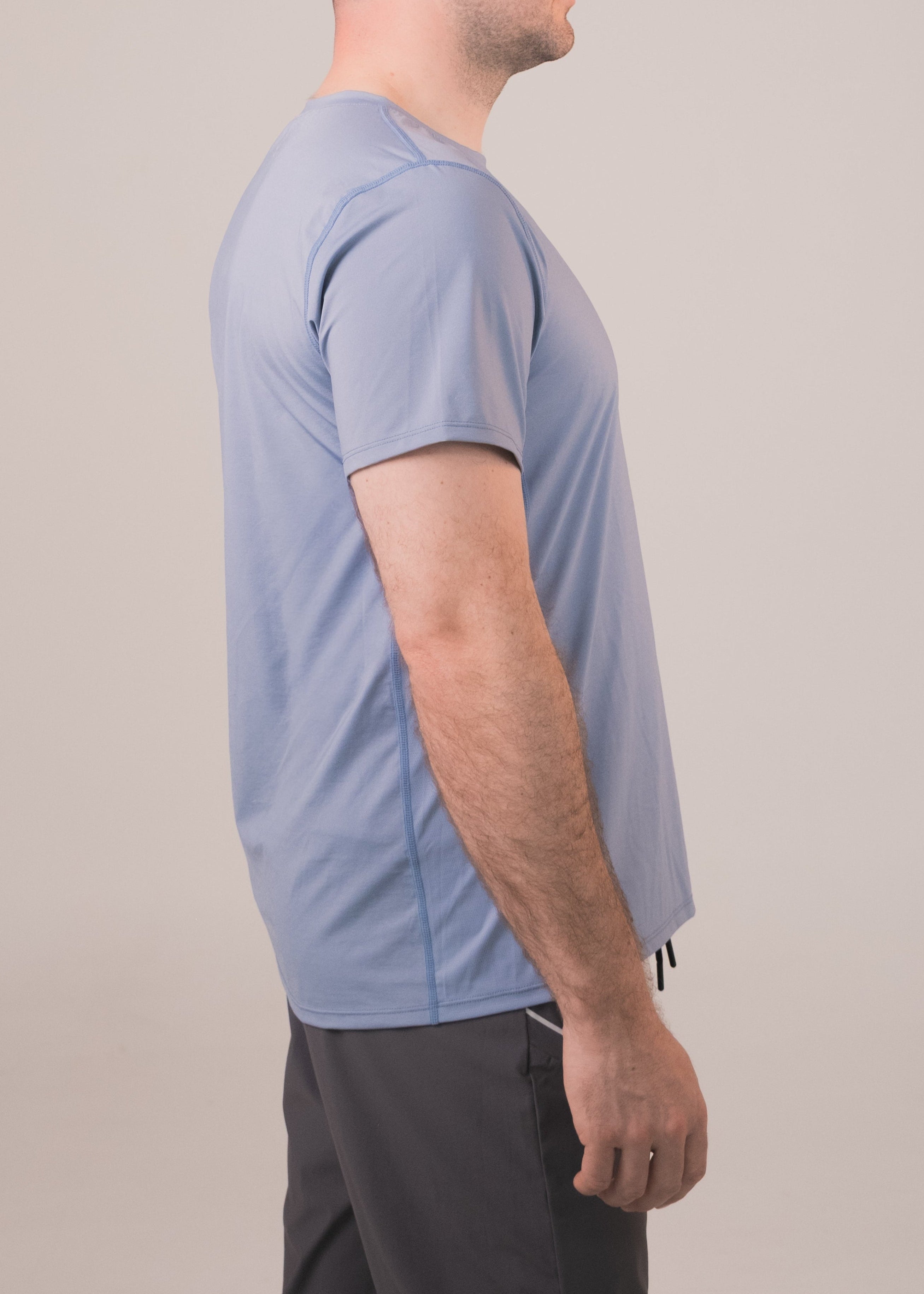Man wearing a light blue athletic shirt and dark shorts on a plain background