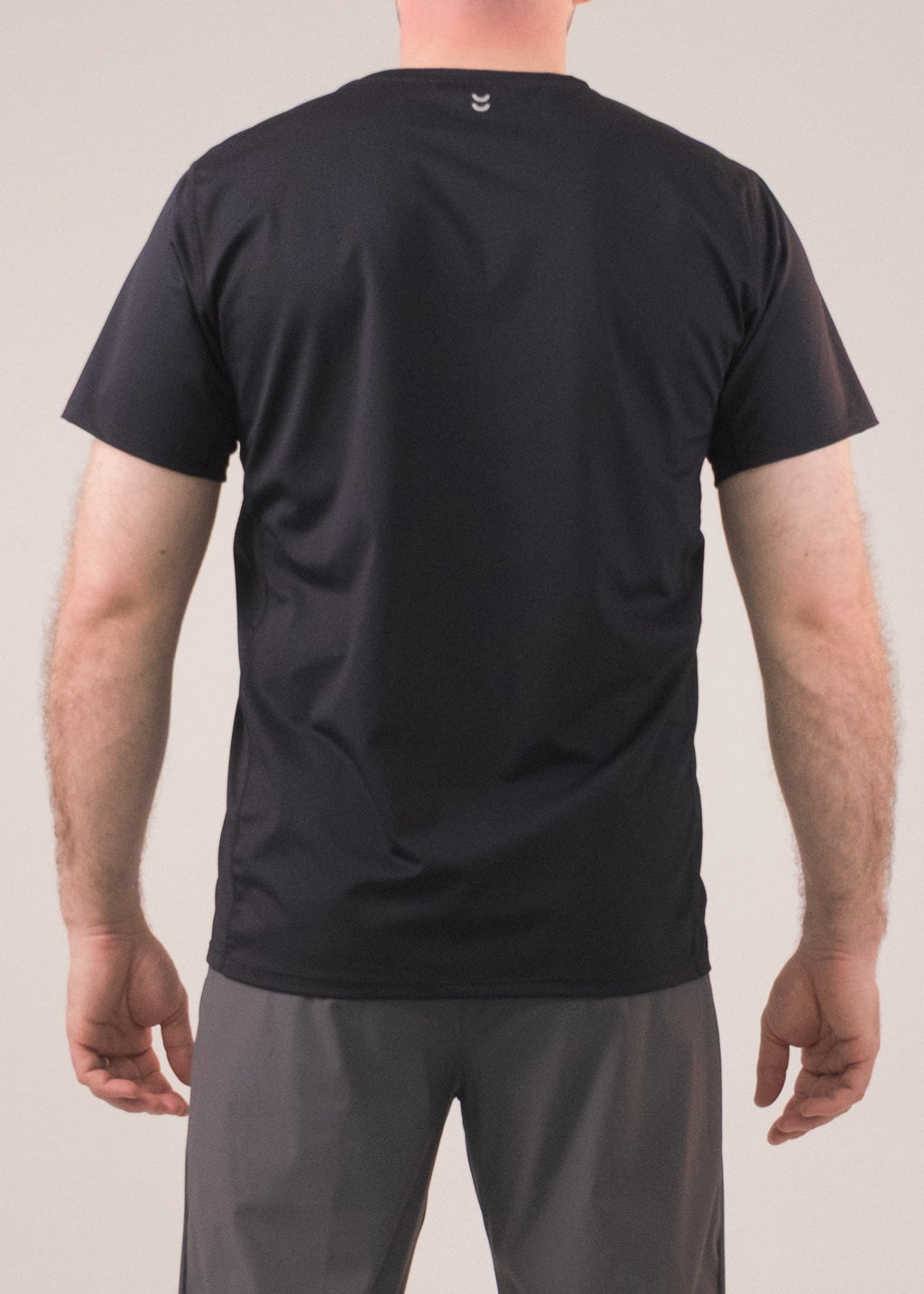 Person wearing a black t-shirt and gray pants on a plain background