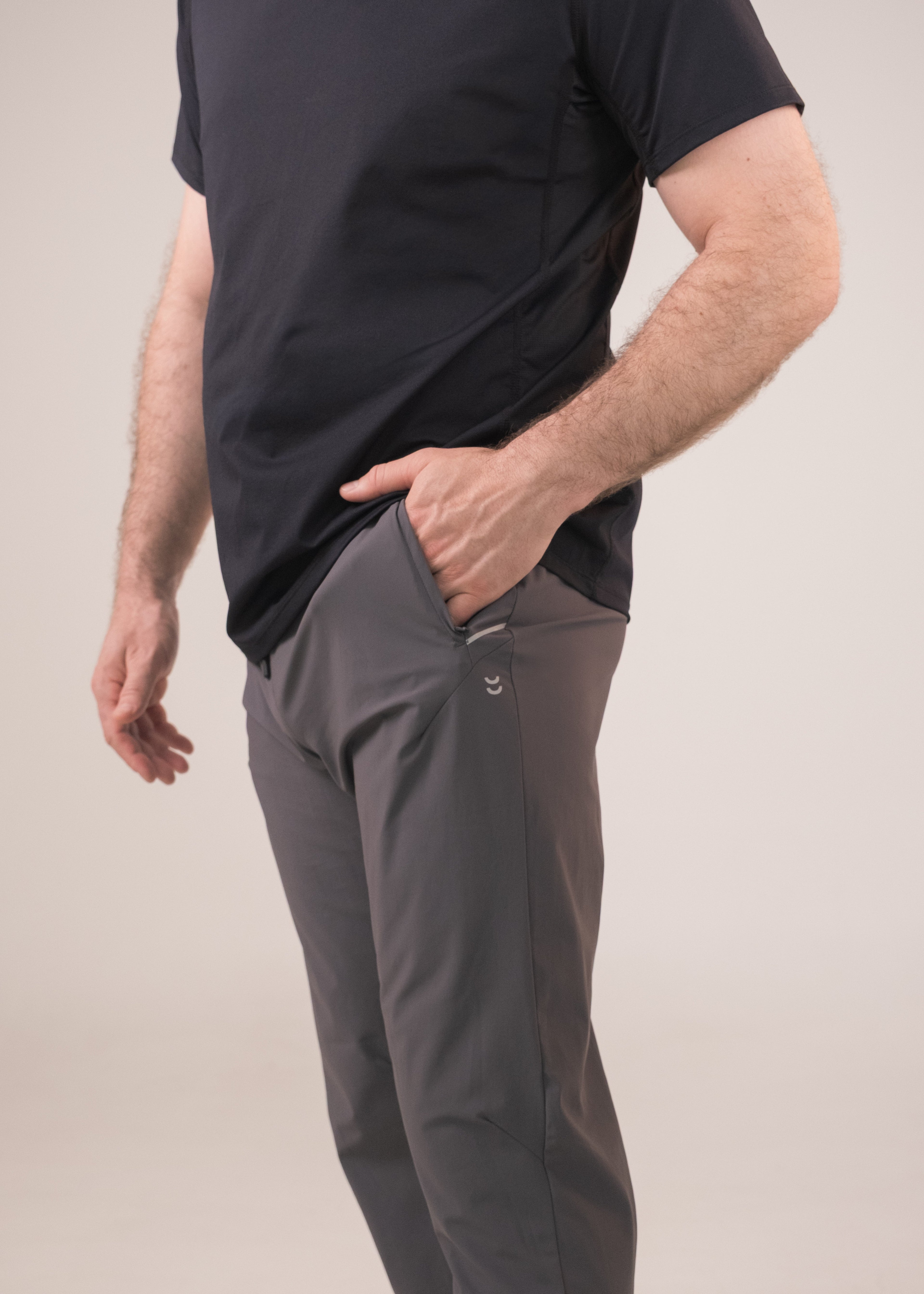 Person wearing a black t-shirt and gray pants on a plain background