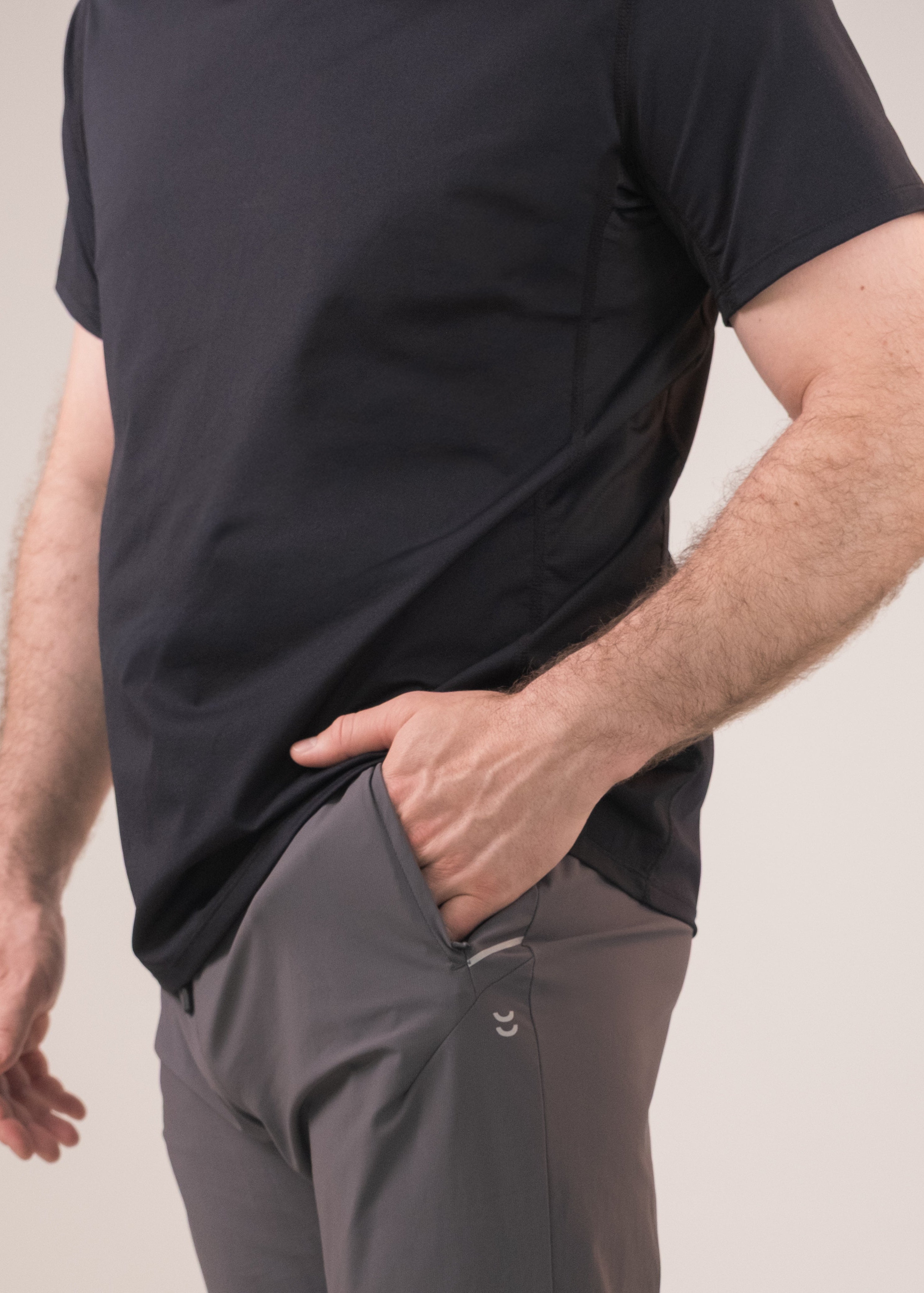 Person wearing a black t-shirt and gray pants on a beige background