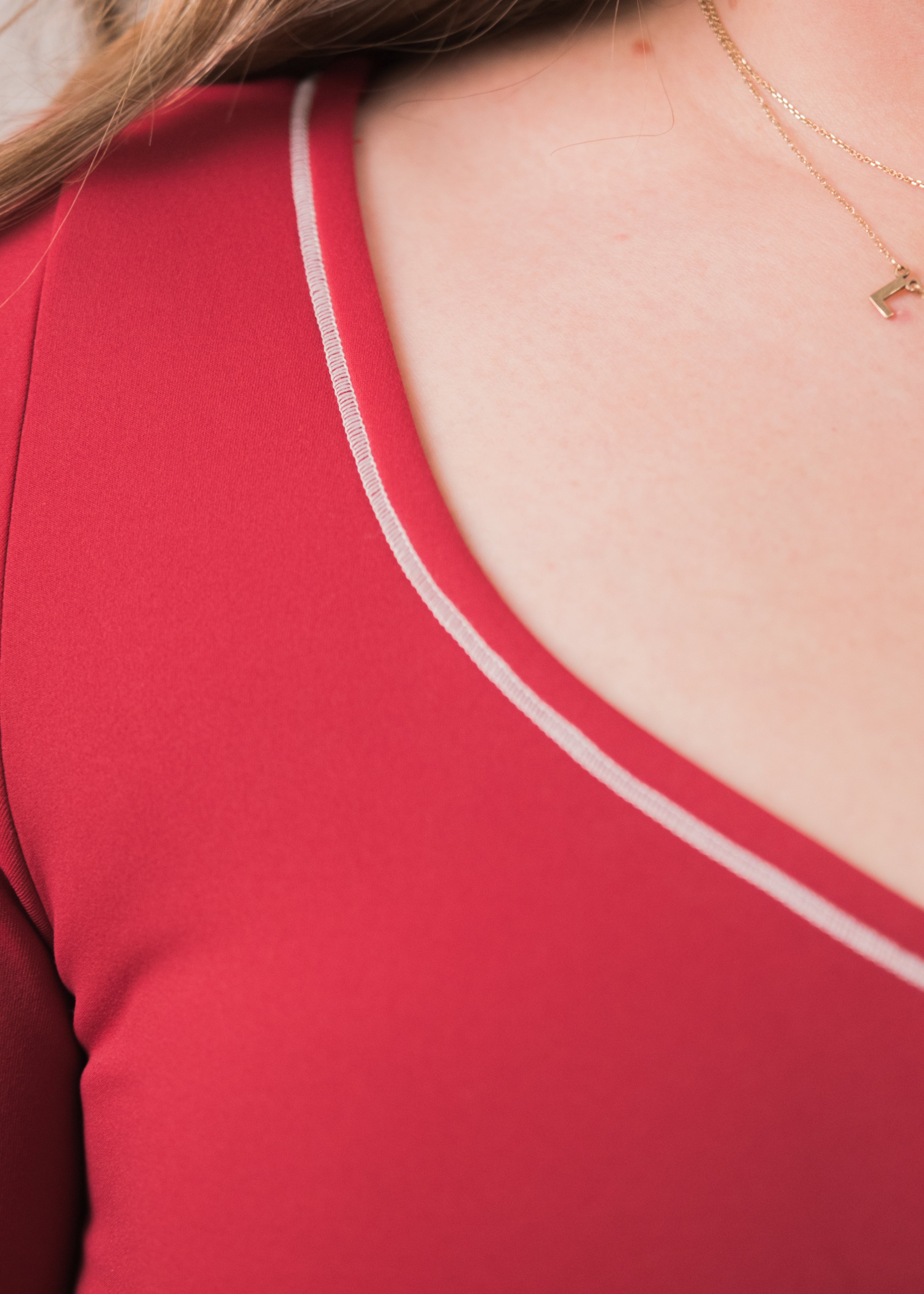 Red tank top with thin straps worn by a person, close-up on neckline.