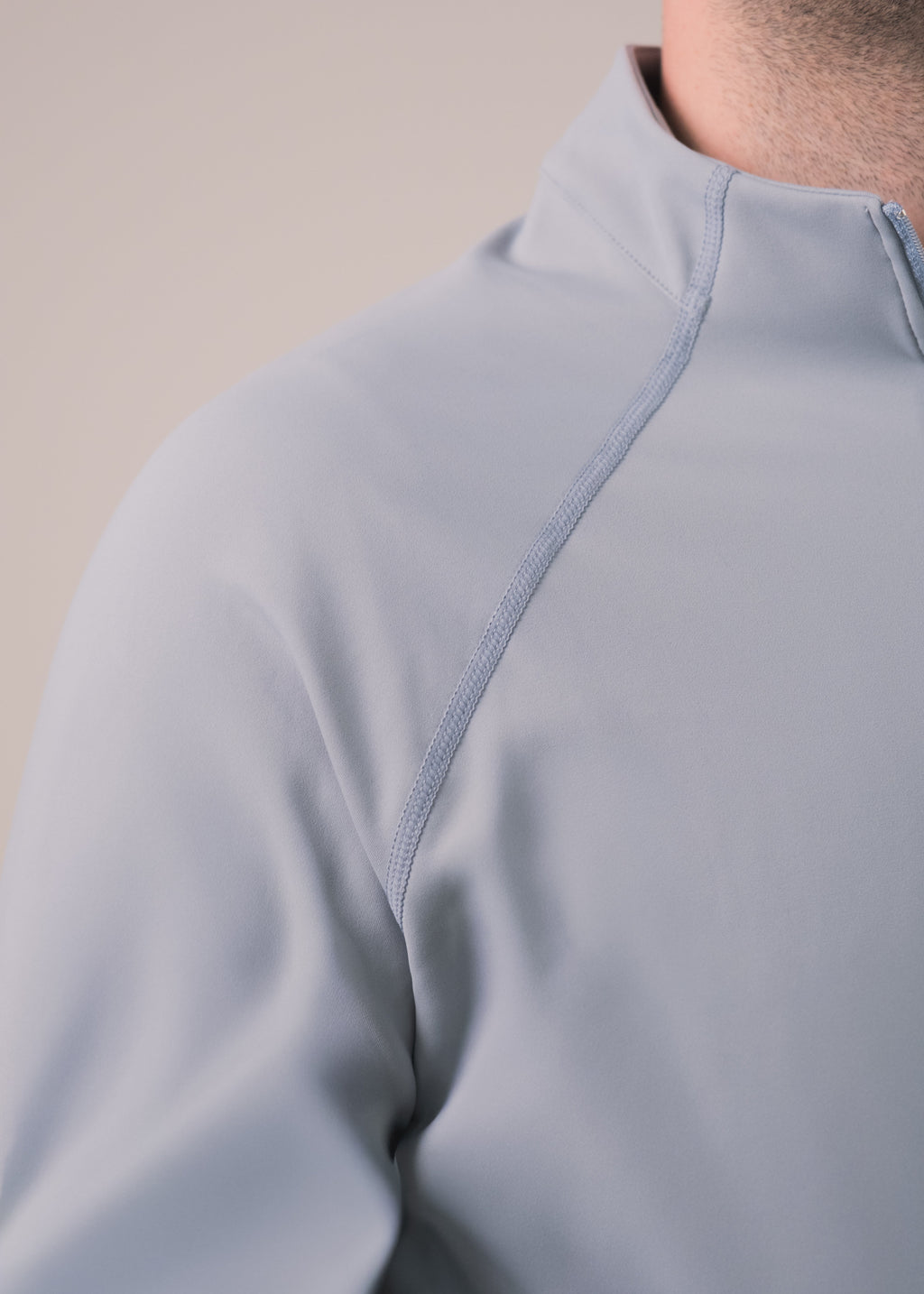 Close-up of a light gray pullover with a zipper on a beige background