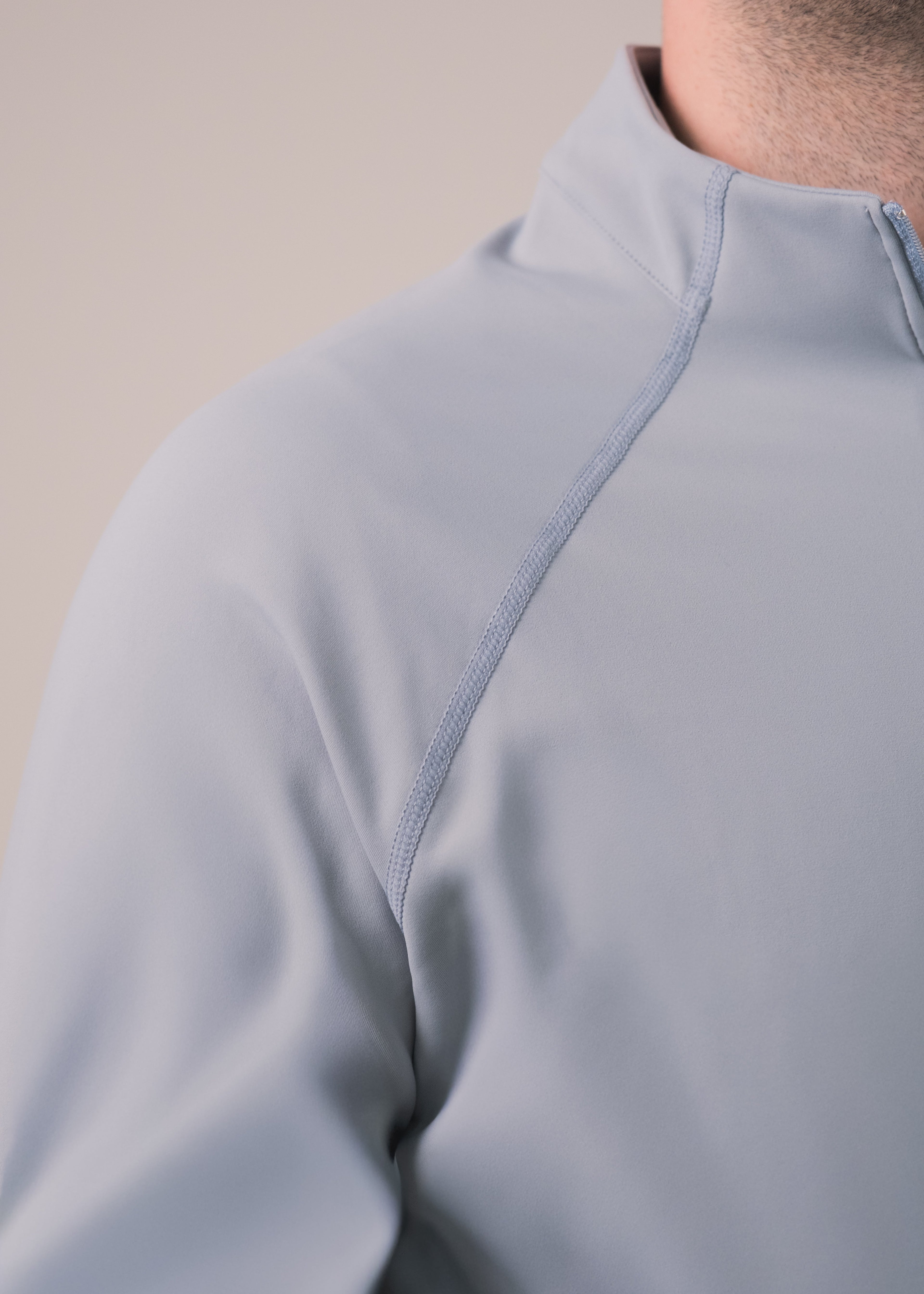 Close-up of a light gray pullover with a zipper on a beige background