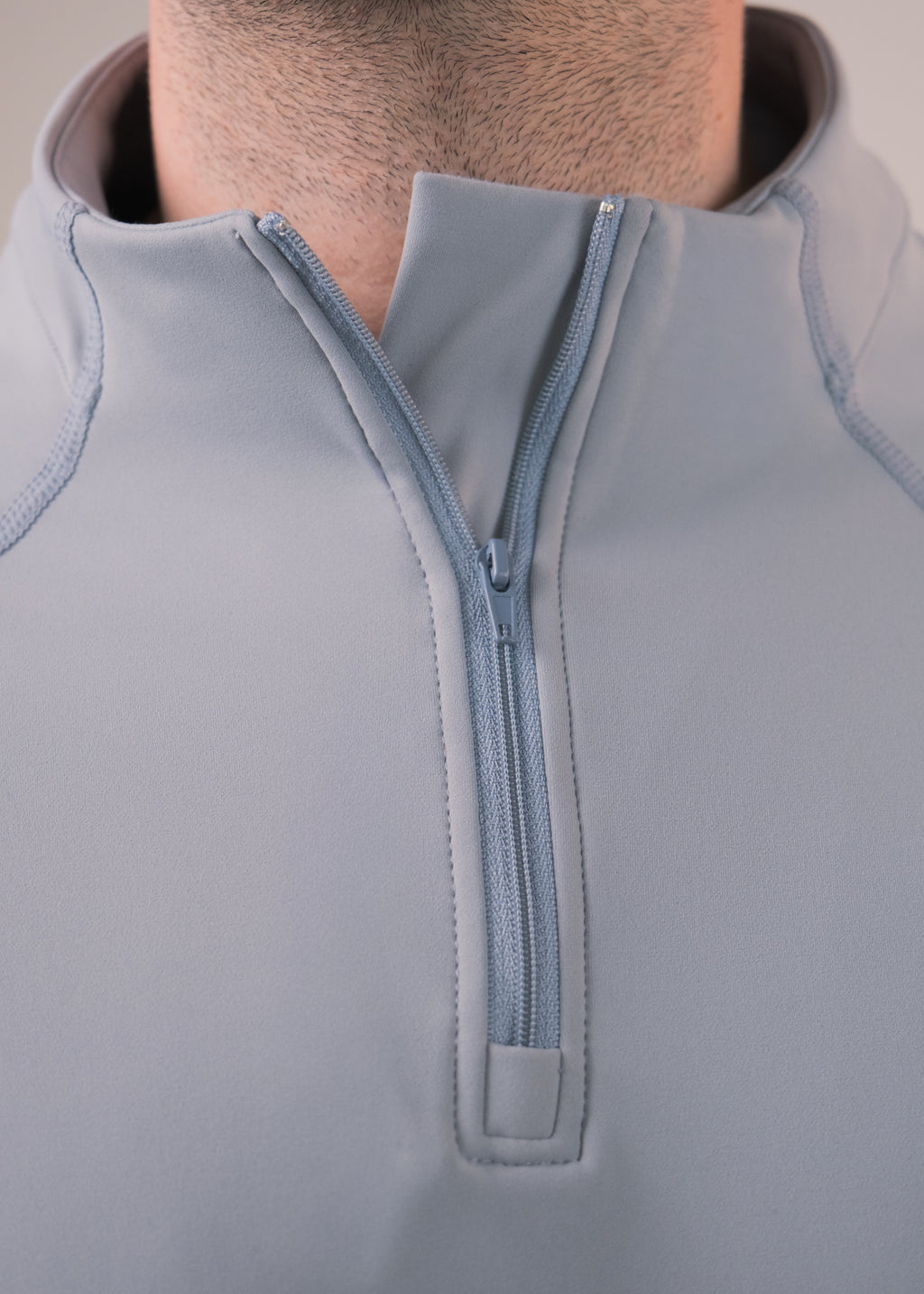 Close-up of a gray zip-up garment with a quarter zip design.