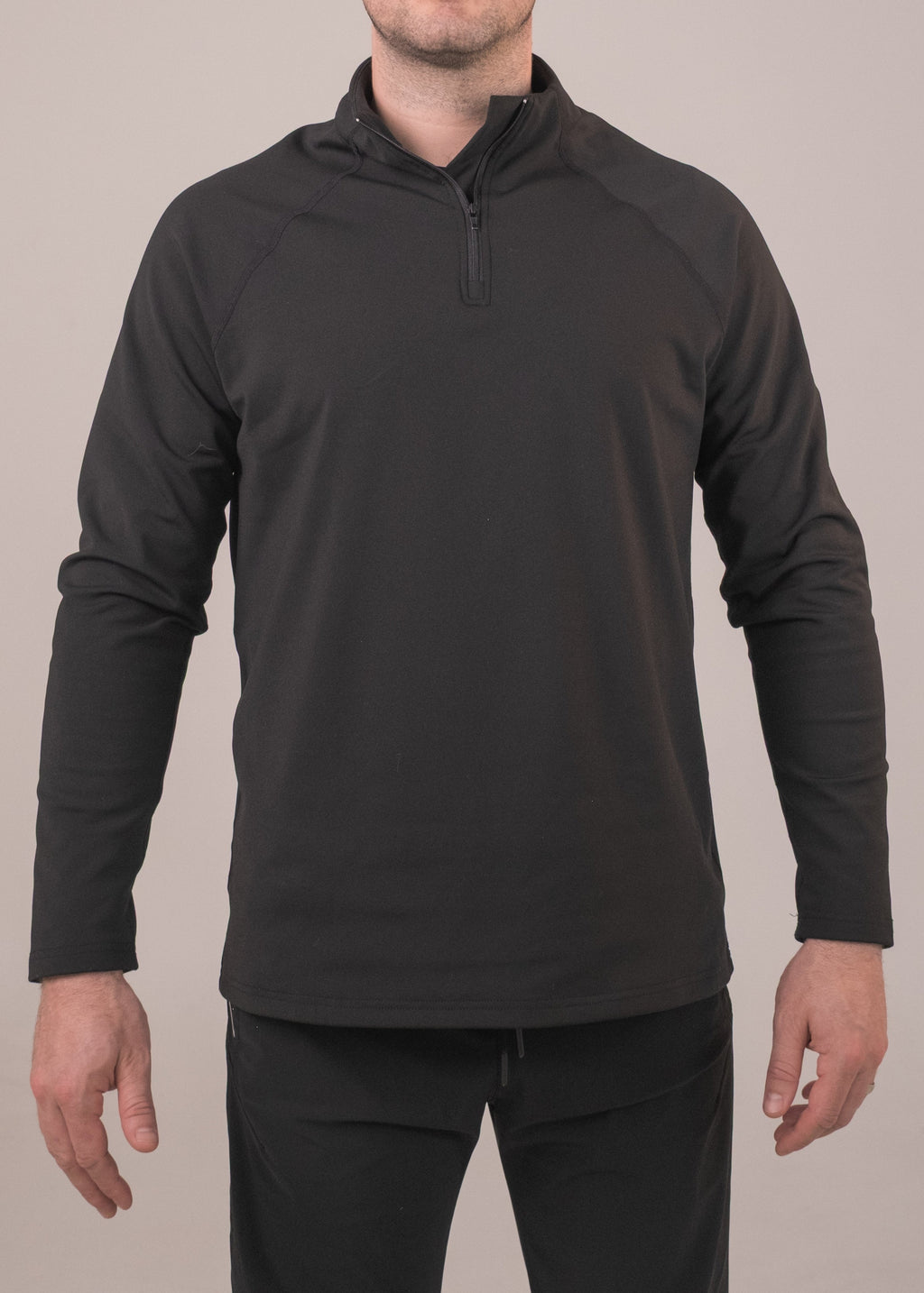 Man wearing a black long-sleeve pullover with a quarter-zip on a plain background