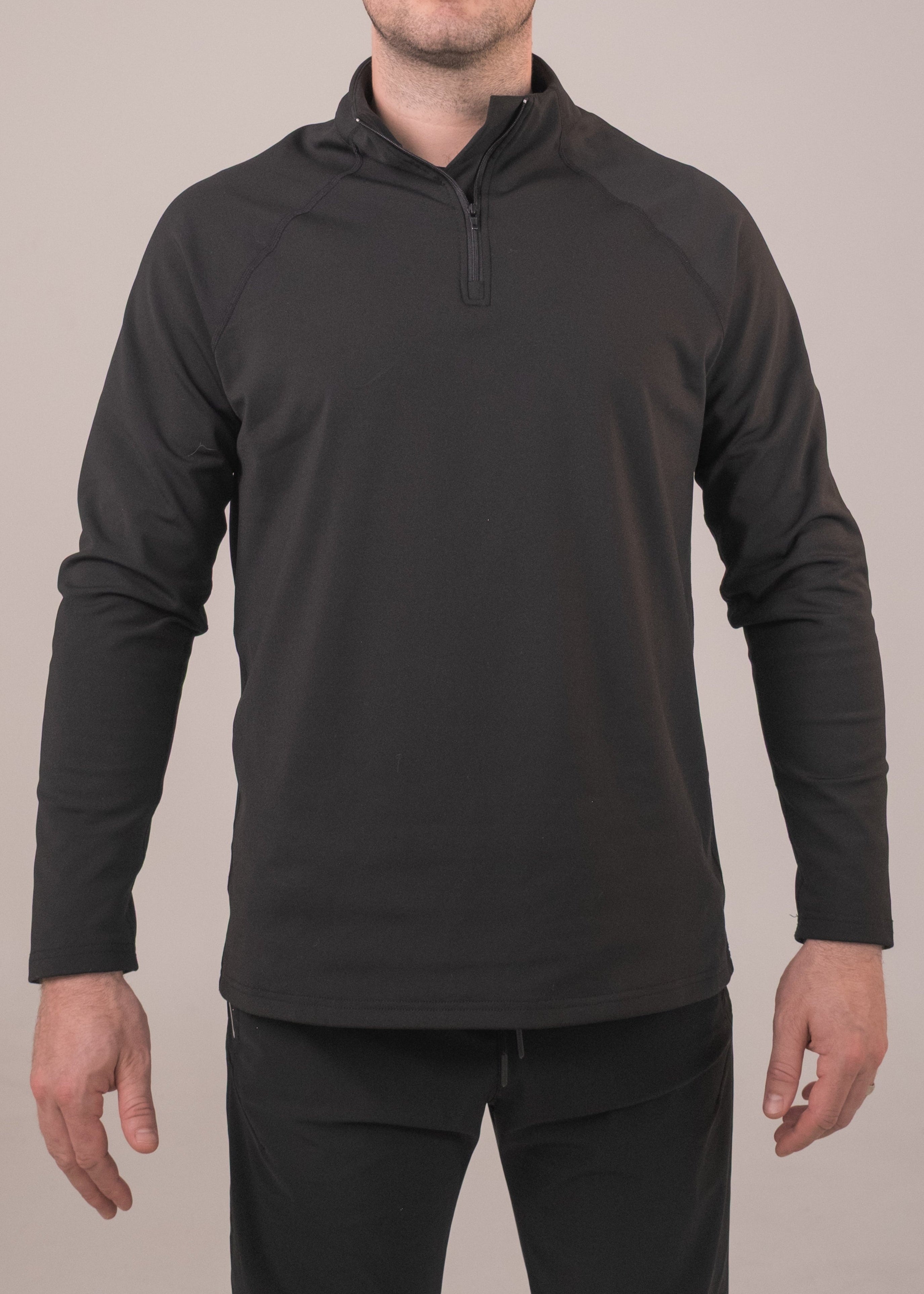 Man wearing a black long-sleeve pullover with a quarter-zip on a plain background