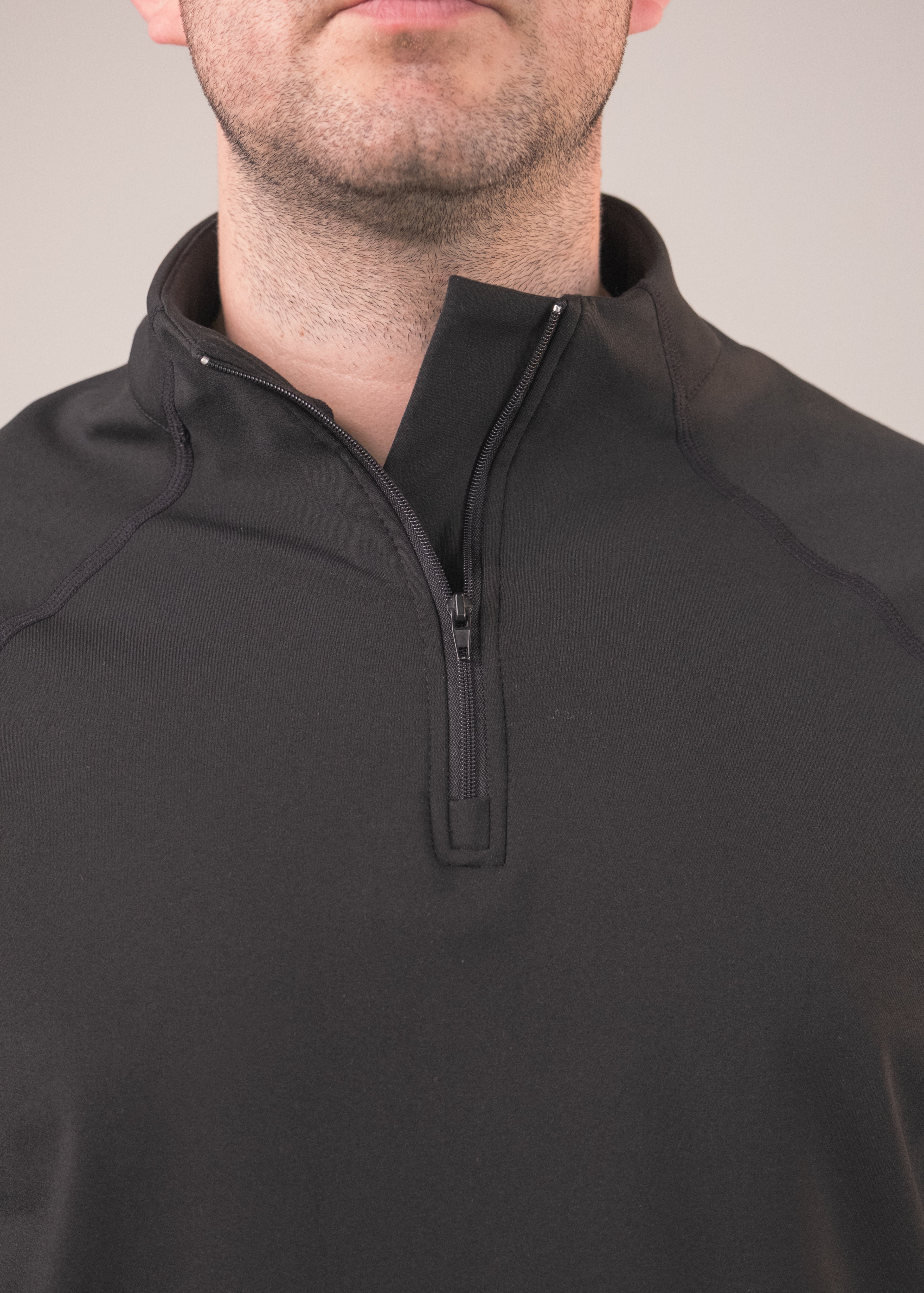 Black quarter-zip pullover worn by a person on a gray background