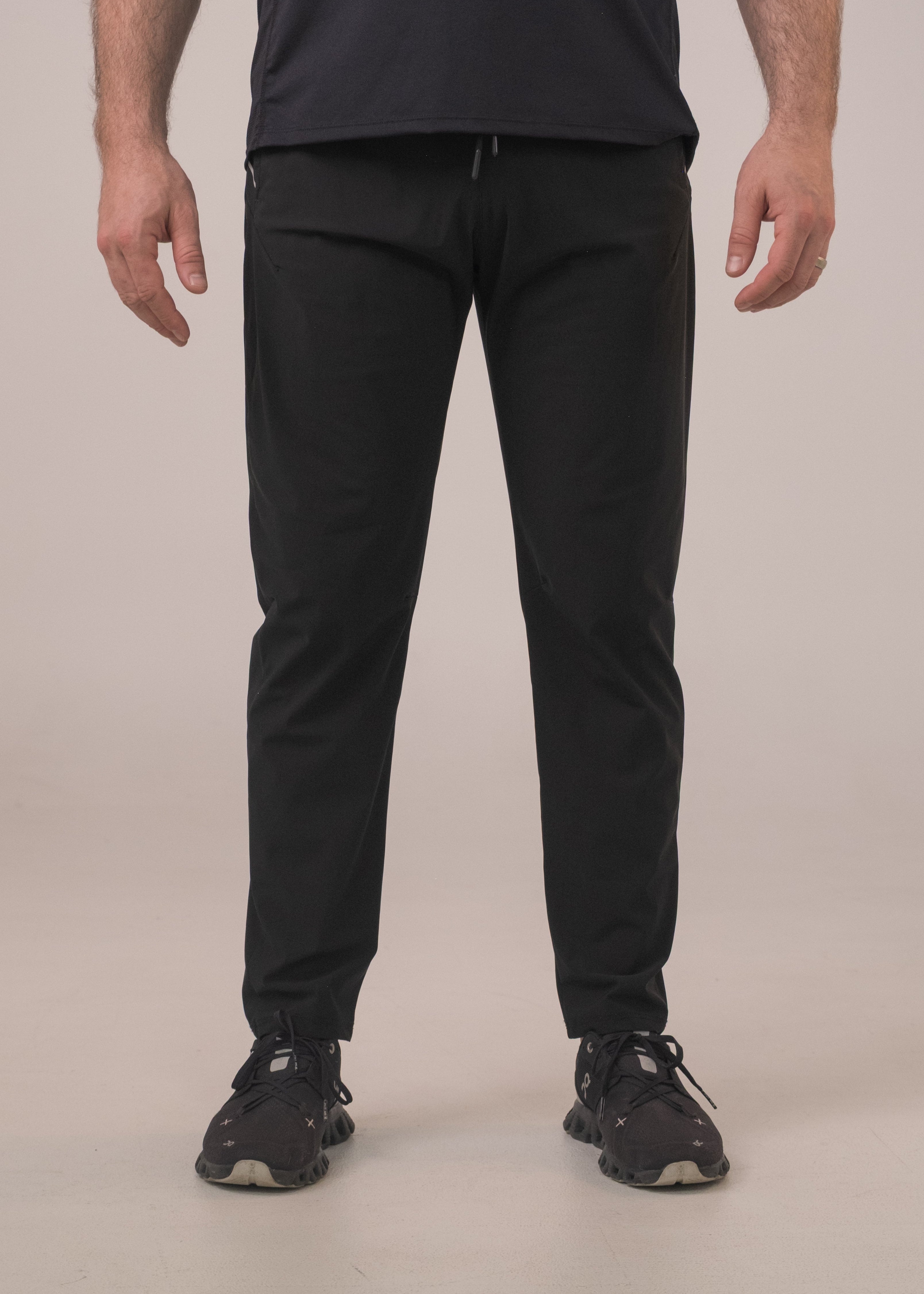 Person wearing black pants and black shoes on a beige background