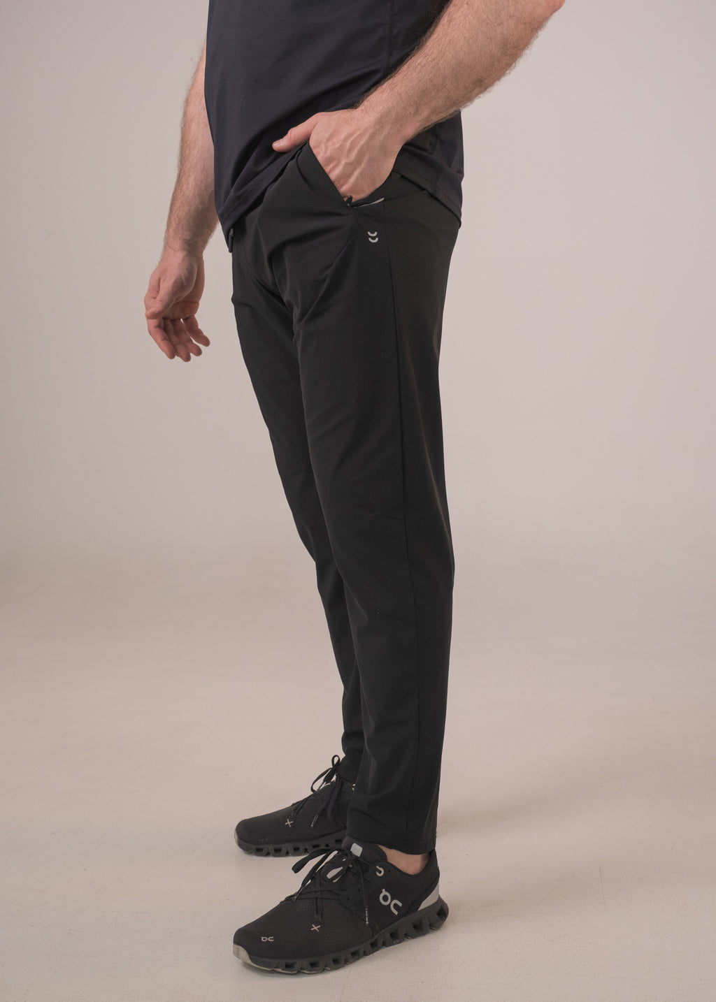 Person wearing black pants and shoes on a beige background