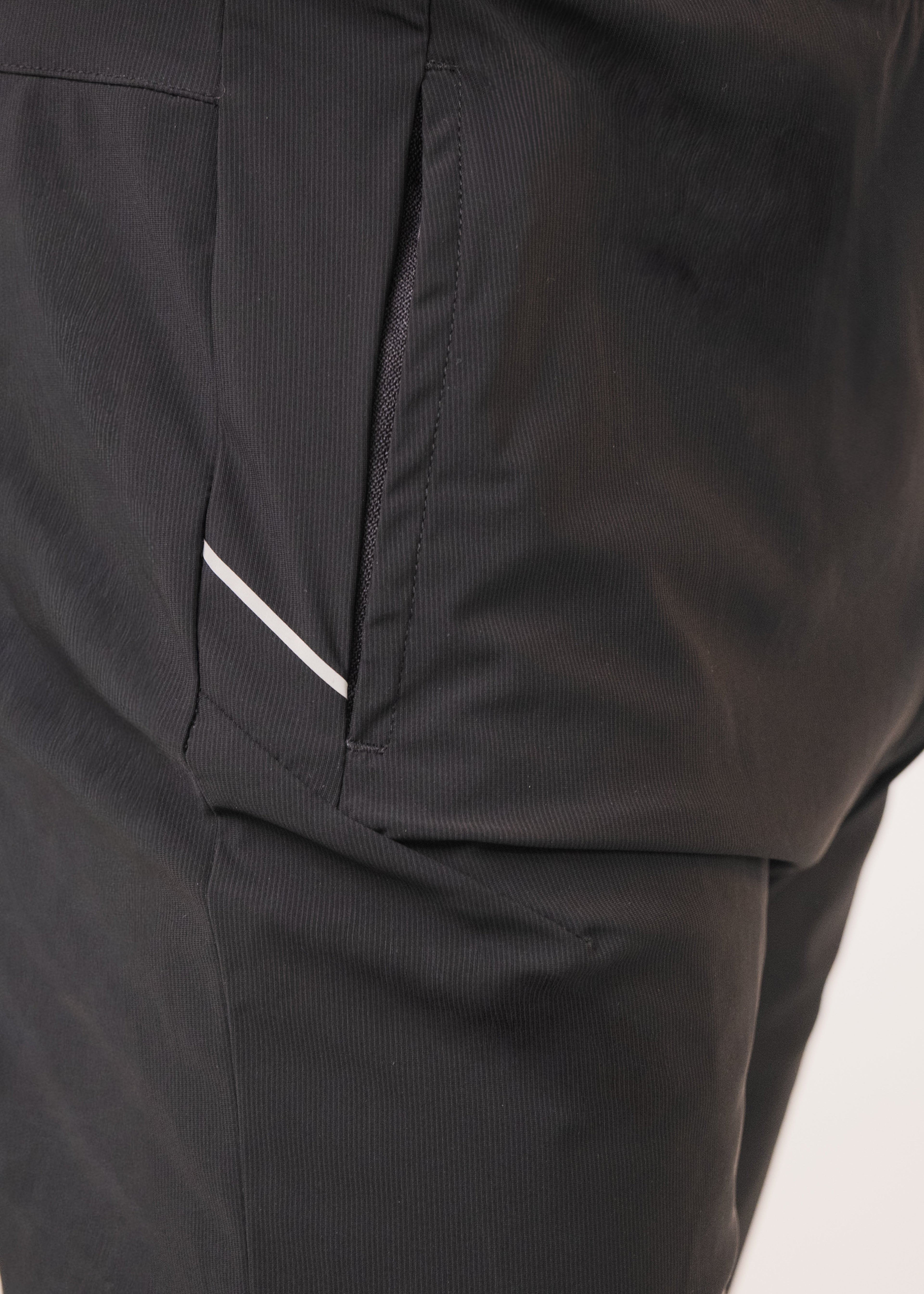 Close-up of black pants with a white stripe on a light background