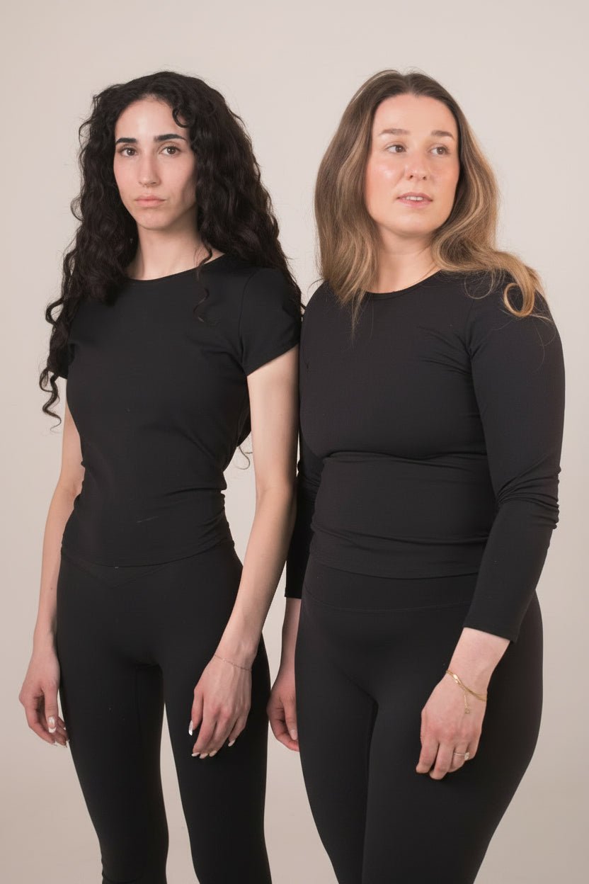 Two women wearing black athletic outfits against a plain background