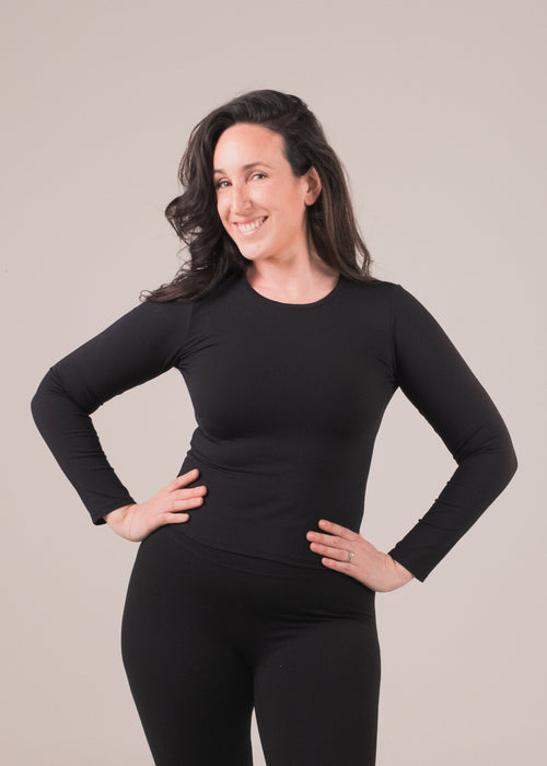 Woman wearing a black long-sleeve top and leggings on a beige background