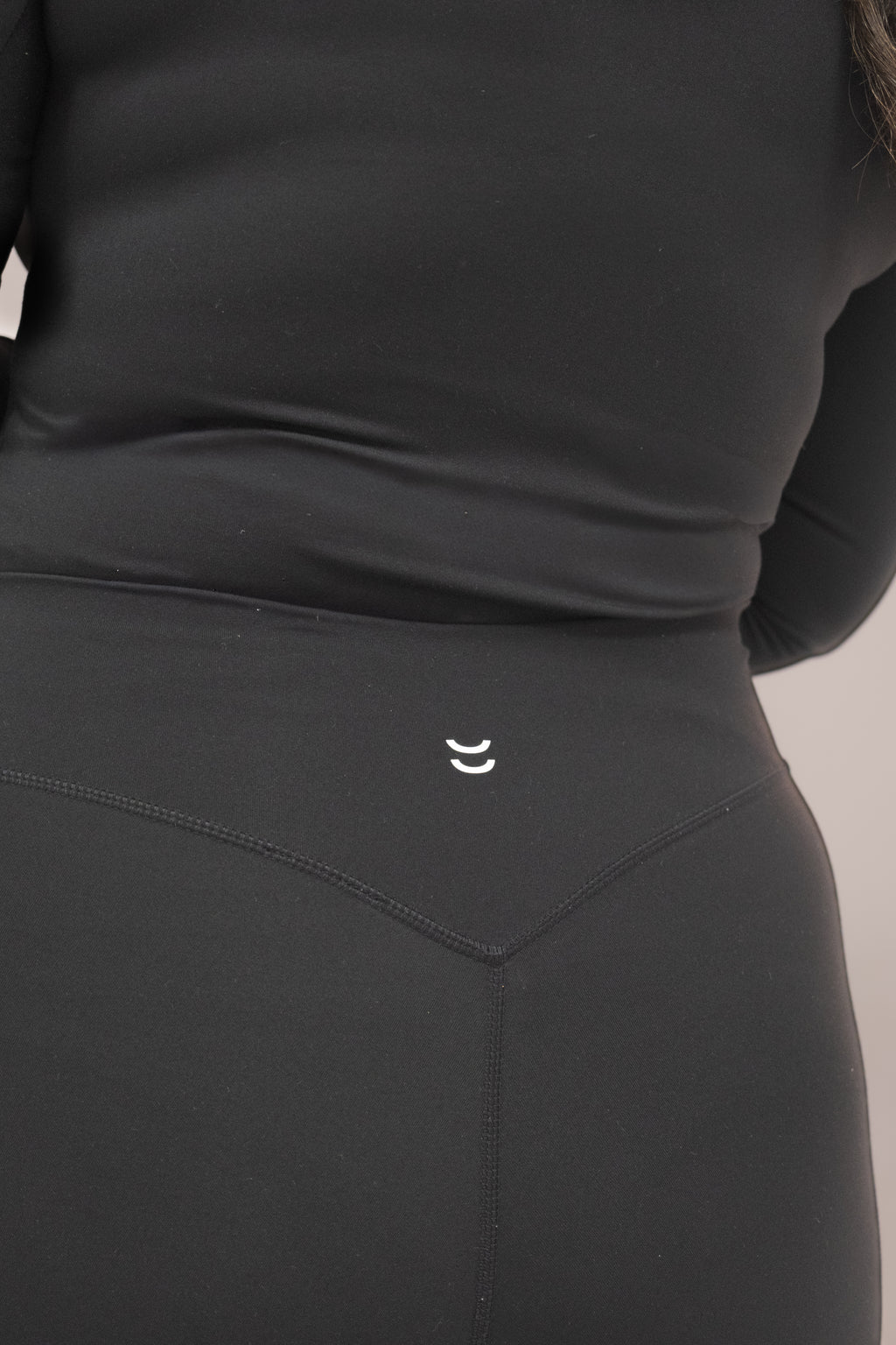 Black athletic outfit with a small logo on the waistband against a neutral background
