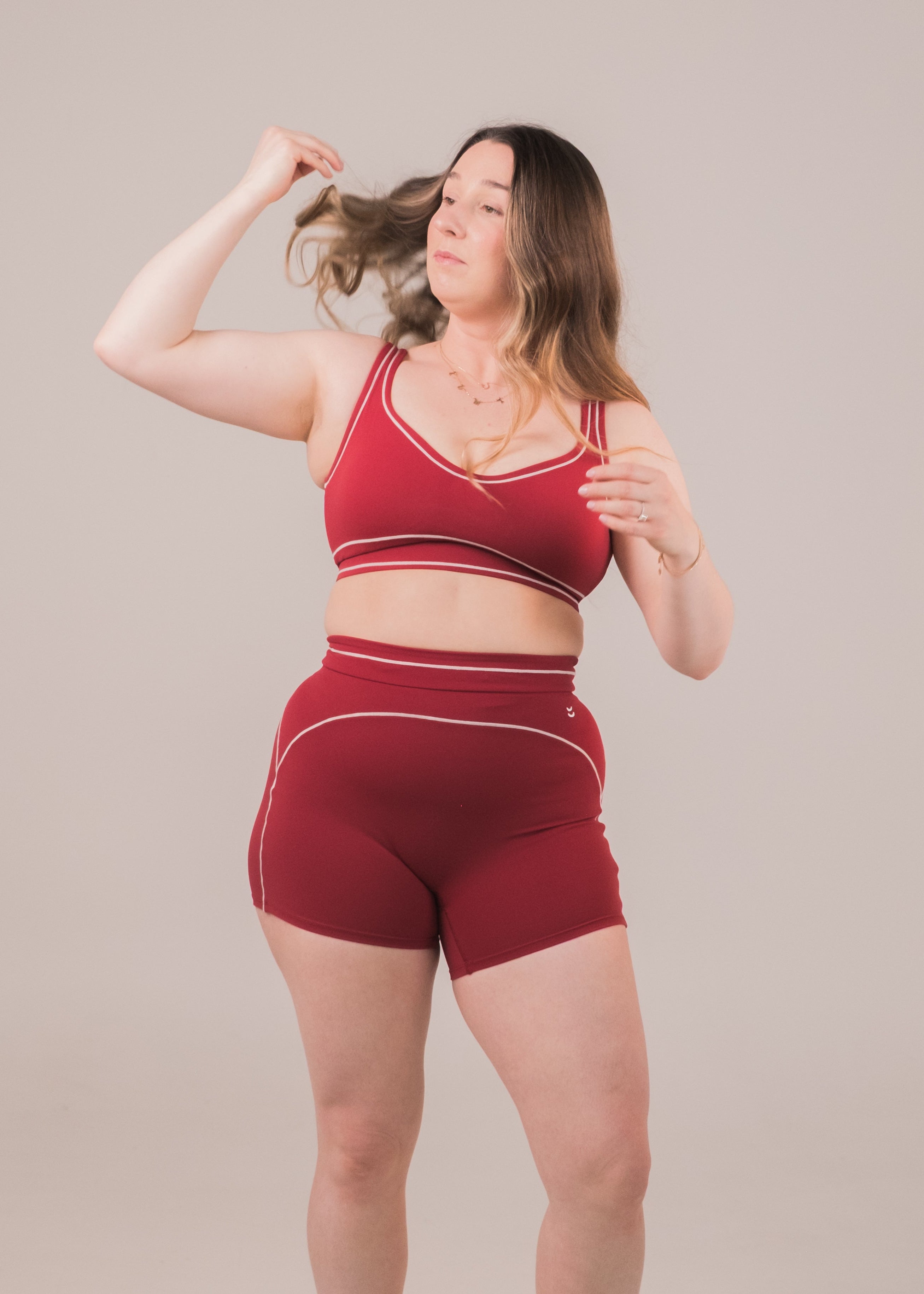 Woman wearing a red sports bra and shorts set on a plain background