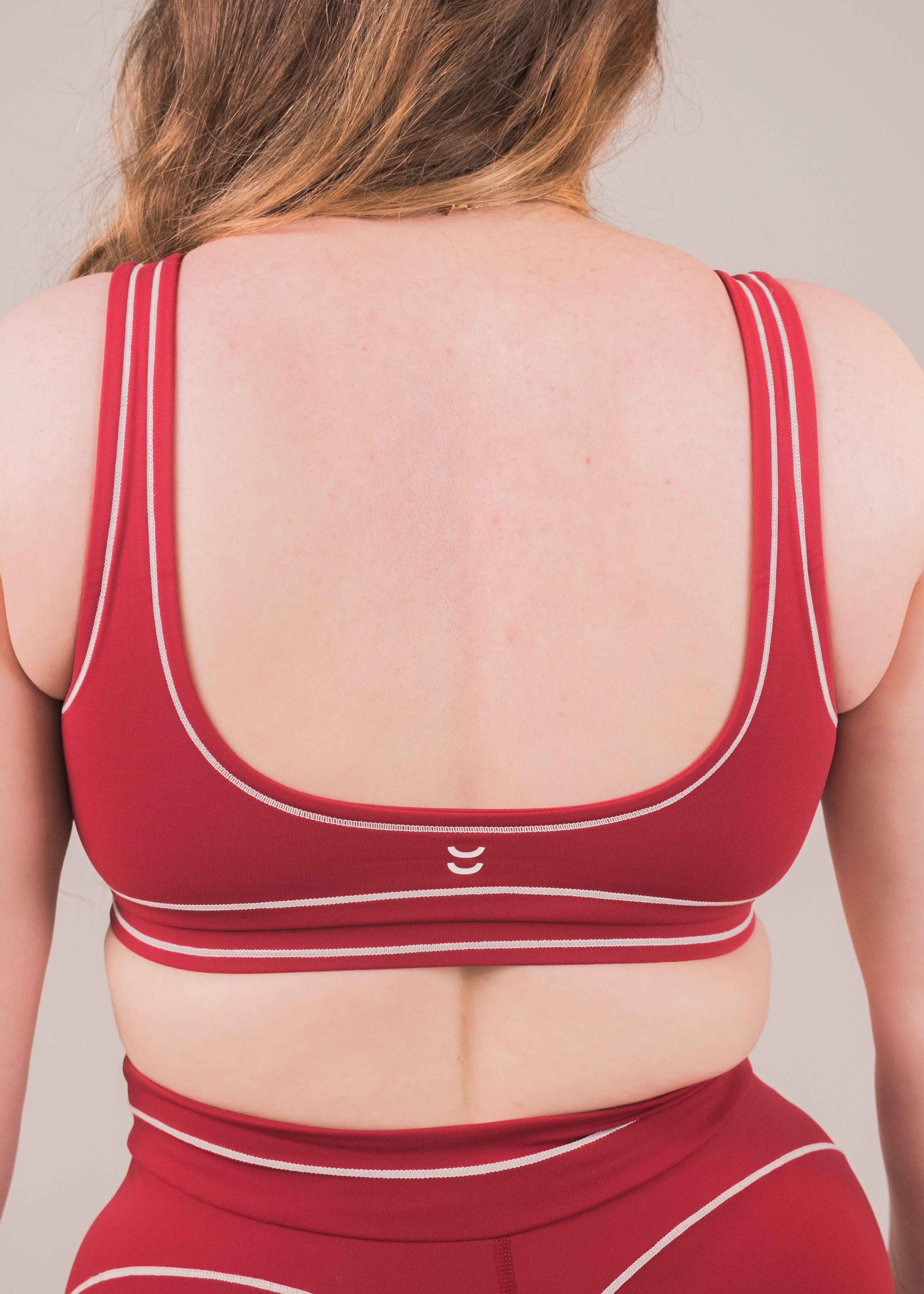 Red sports bra and leggings set with a visible brand logo on a neutral background