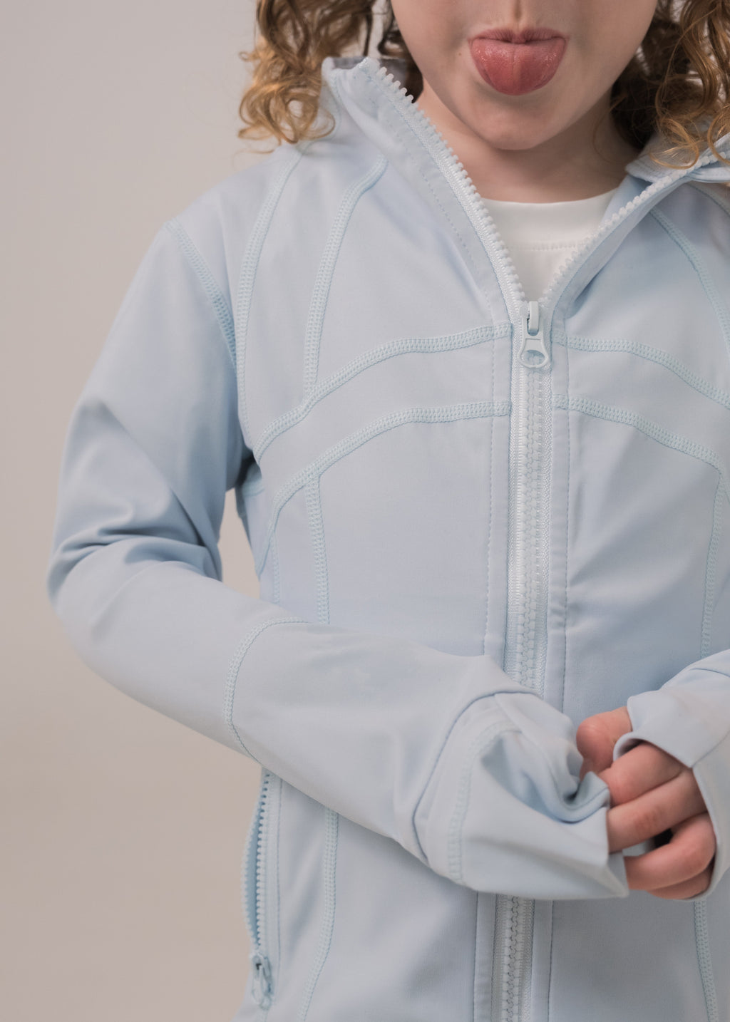 Person wearing a light blue jacket with a neutral background