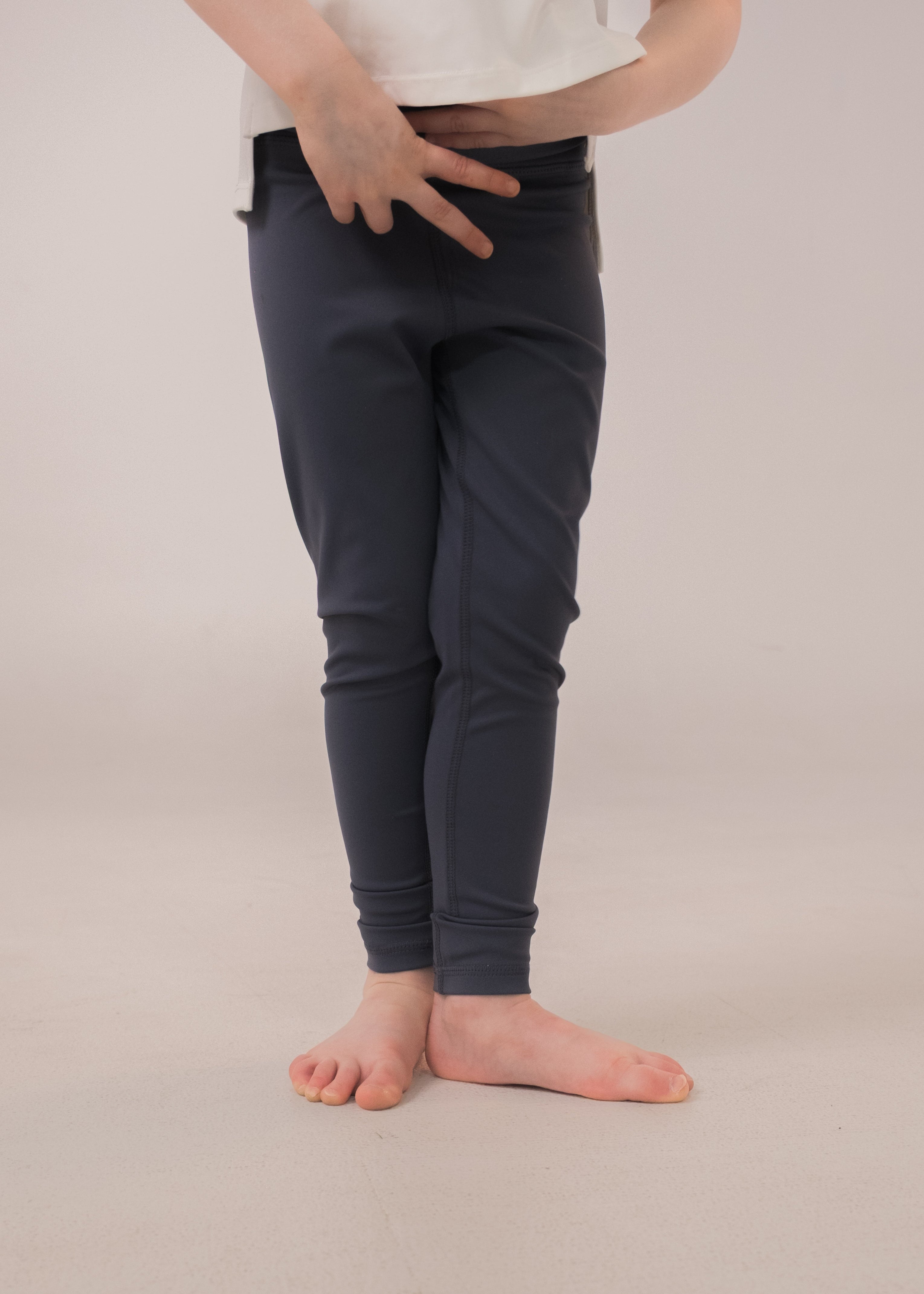 Person wearing dark gray leggings on a plain background