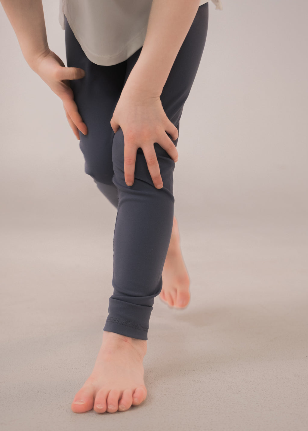 Person wearing dark gray leggings on a beige background