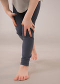 Person wearing dark gray leggings on a beige background