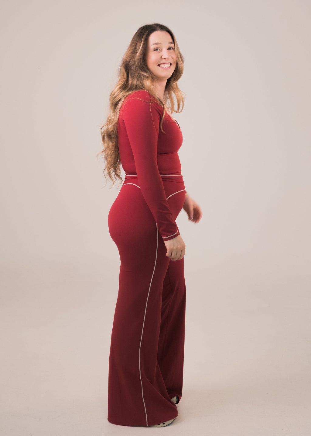 Woman wearing a red dress with long sleeves on a beige background