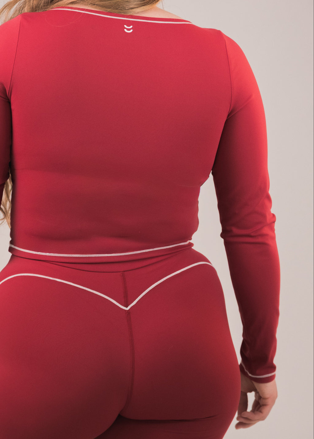 Person wearing a red long-sleeve top and leggings set on a plain background