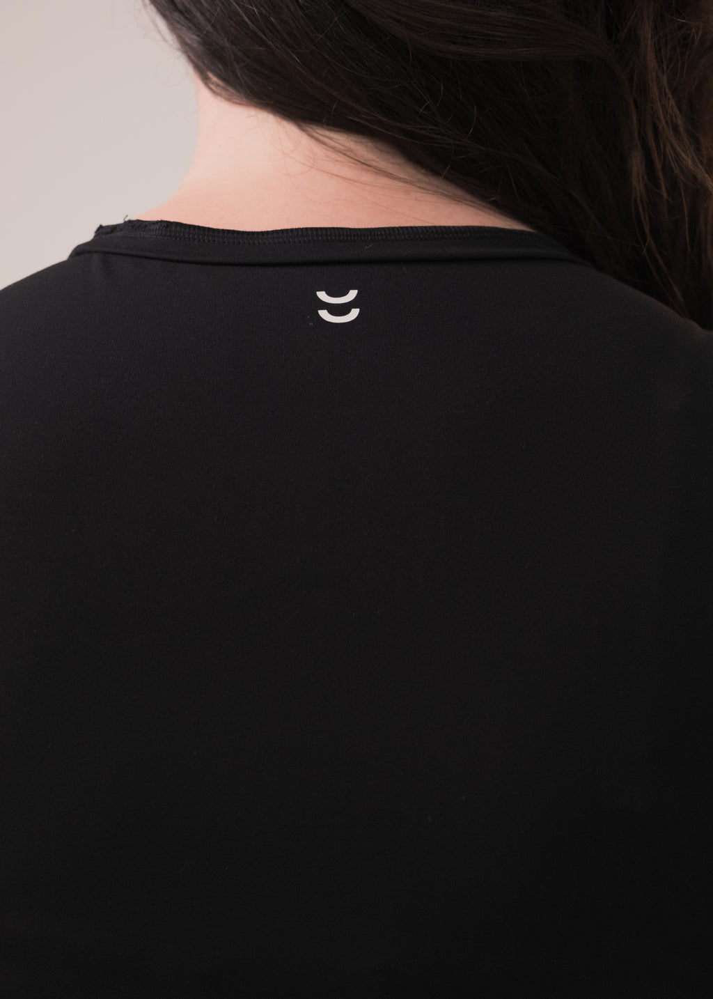 Black shirt with a small white logo on the collar against a neutral background